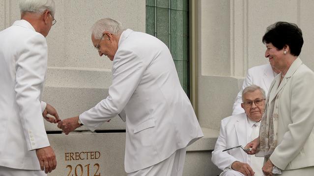 Vârstnicul L. Tom Perry, din Cvorumul celor Doisprezece Apostoli, pune mortar în jurul pietrei din capul unghiului a Templului Brigham City Utah în timp ce soţia sa, Barbara, priveşte.